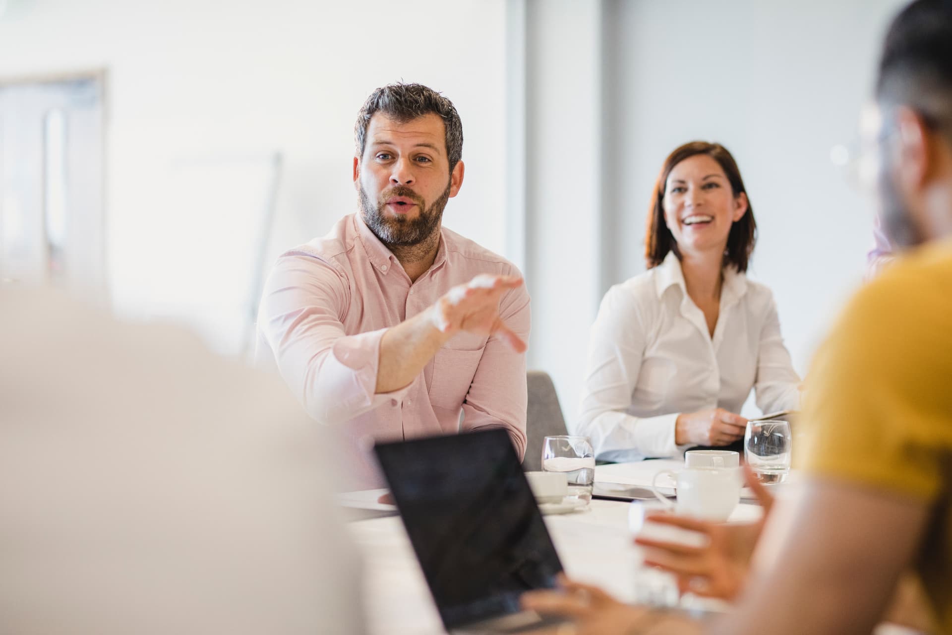 Colleagues discussing around a boardroom table in a bright meeting room
